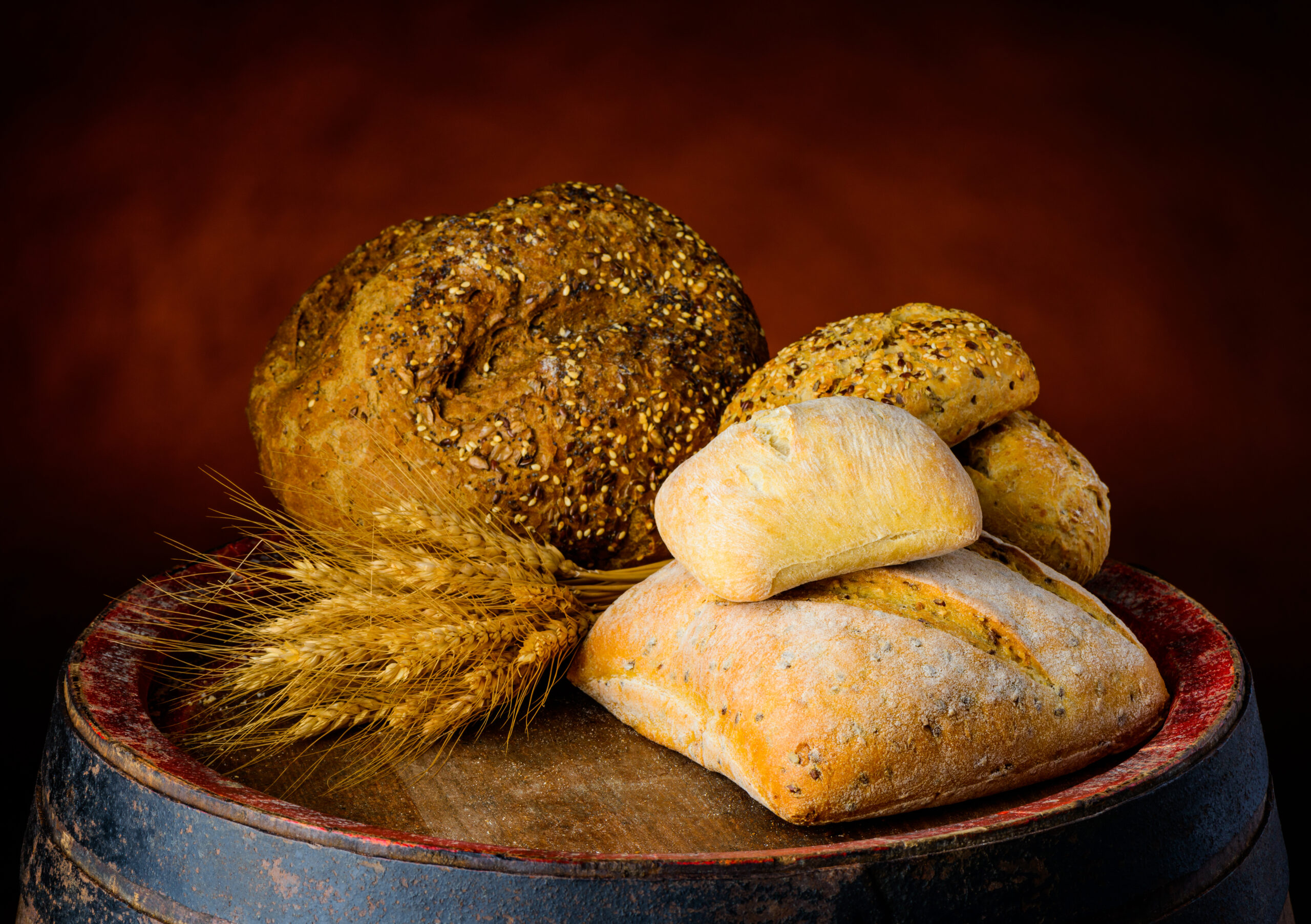 Different bread types and bun on wooden barrel. rustic, traditional composition.